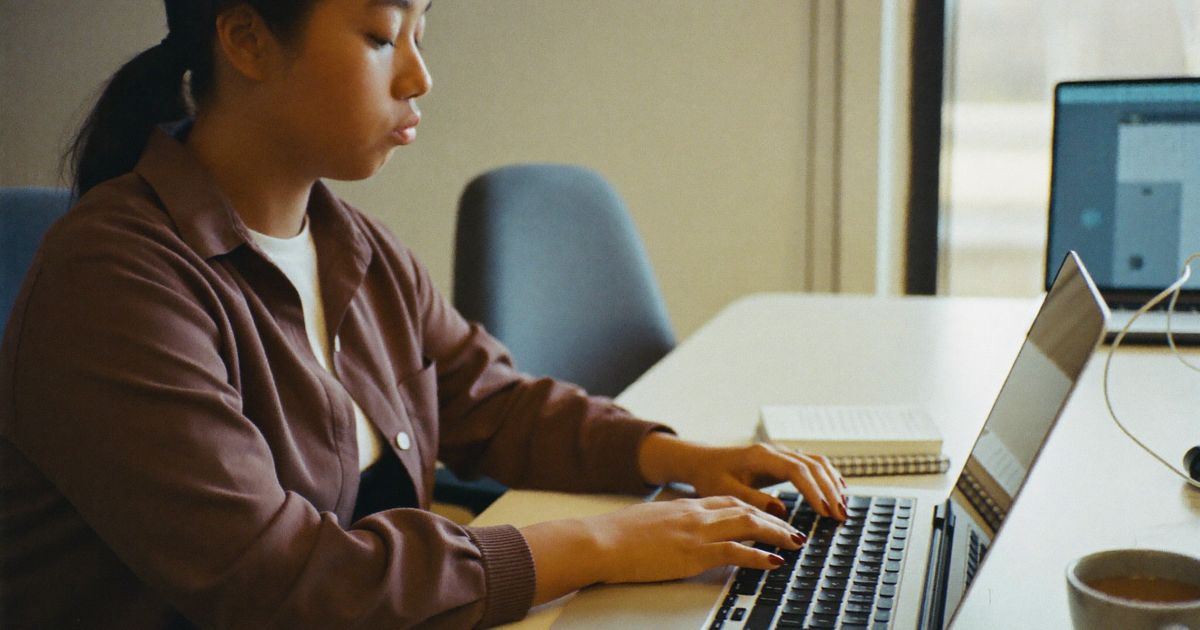 Why do I apologise so much: a young woman pauses over her laptop at work, second-guessing a message before she sends it
